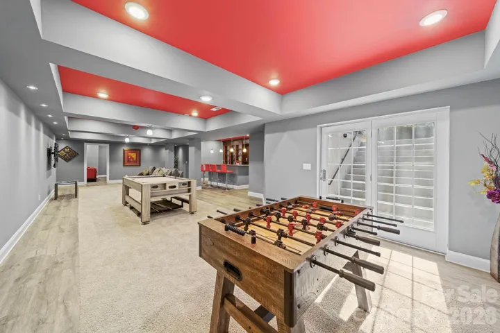 Expansive lower-level recreation room designed for entertaining, featuring custom tray ceilings, multiple gathering areas, and seamless flow to the outdoor patio