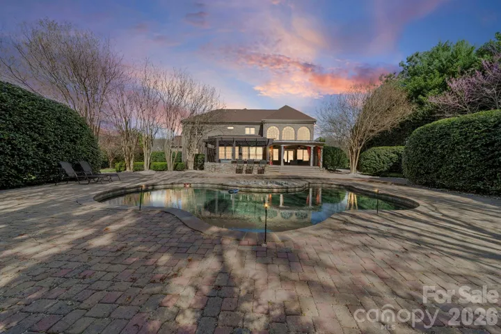 Stunning brick estate beautifully illuminated at twilight, showcasing timeless architecture, manicured landscaping, and exceptional curb appeal.