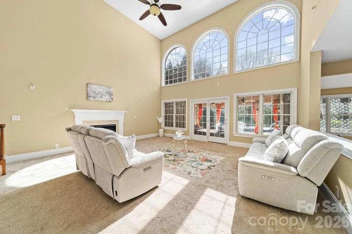 Dramatic two-story great room filled with natural light, showcasing soaring arched windows and serene views—creating an impressive yet inviting space to relax and entertain.