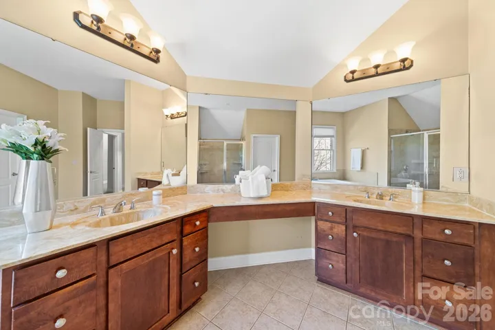 bathroom with dual vanities, generous counter space, and wall-to-wall mirrors—offering both style and functionality.