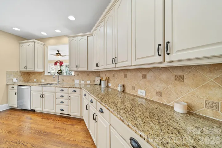 Elegant chef’s kitchen featuring expansive granite countertops, custom cream cabinetry, and a timeless tile backsplash—designed for both everyday living and effortless entertaining
