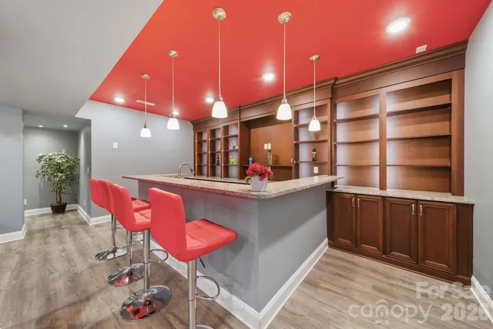 Elegant built-in wet bar with granite countertops, custom wood cabinetry, wine storage, and bar seating—perfect for hosting game nights or relaxing with guests.