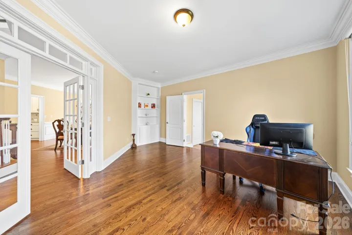 Spacious executive office with hardwood floors, elegant crown molding, and French doors—an ideal work-from-home retreat offering both style and privacy
