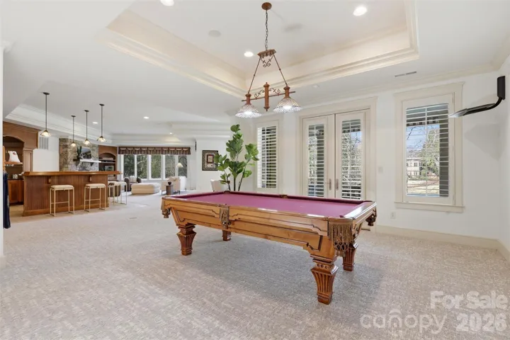 The basement opens up. Billiard table, full ceiling height, bar steps away. This is a second home beneath the first.