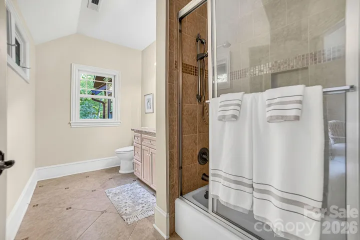 Ensuite bathroom with glass mosaic tile inlays and a gorgeous stone vanity and framed mirror.