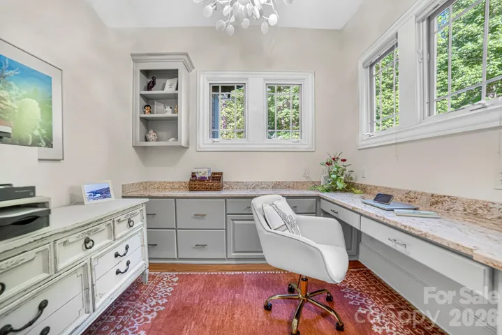 Of two offices, one is located adjacent to the kitchen and includes built in cabinetry with shelving, drawers and file storage.