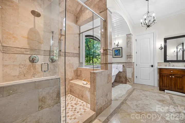 A cabinet with glass doors is ideal for storing linens.  The generously sized shower includes a ledge, window and rain and hand shower heads. Two finished walk-in closets complete this lovely bathroom.