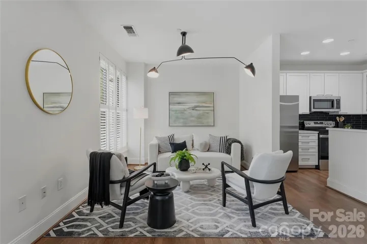 Open-concept living at its finest with a designer 3-arm chandelier, plantation shutters, and a seamless flow into the chef's kitchen making this space as functional as it is stunning.