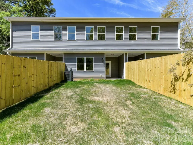 Rear exterior of the townhome featuring a covered patio and private fenced backyard, perfect for outdoor enjoyment and low-maintenance living.