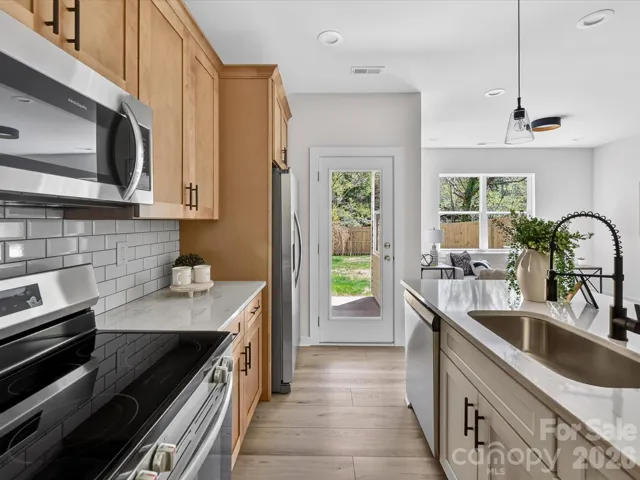 Stylish open-concept kitchen featuring granite countertops, stainless steel appliances, subway tile backsplash, and a spacious island with seating, perfect for everyday living and entertaining.
