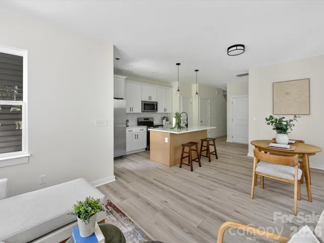 Light-filled open-concept living and dining area with durable flooring, neutral finishes, and a seamless flow into the modern kitchen with island seating.