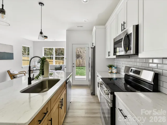 Bright, open-concept kitchen featuring a spacious island with seating, stainless steel appliances, and seamless flow into the sun-filled living area.