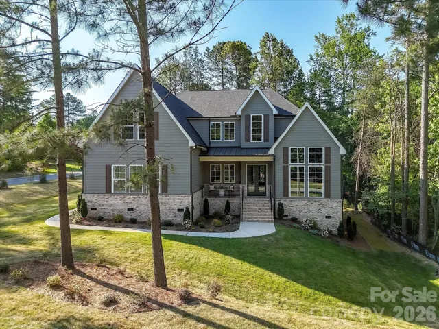 Stunning craftsman-style home with charming covered front porch, stone accents, and nestled on a private, wooded lot offering both curb appeal and peaceful surroundings.