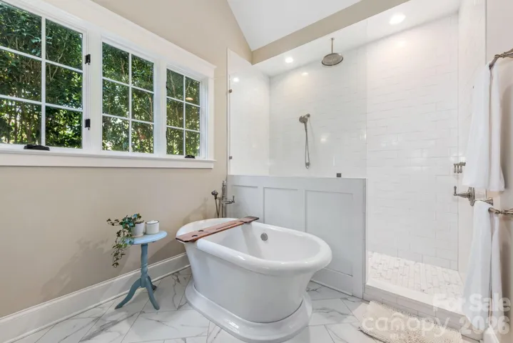 Large freestanding tub and tub filler with shower that includes rain head, handheld shower head, body sprayer and large shower bench.