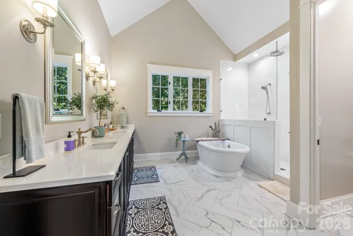 Primary Bath with vaulted ceiling, elegant vanity and natural screening outside