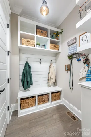 Mudroom has built-in drop zone, shelves for smaller items like keys and purses and a large closet for supplies with access to a/v panel. 