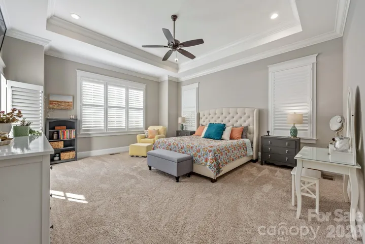 Primary Bedroom includes tray ceiling, lots of windows and custom plantation shutters. 