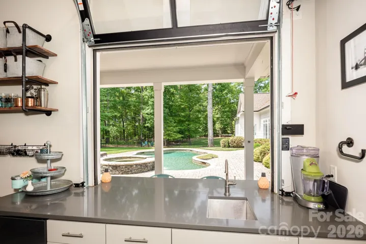 View from inside pool house looking out. Bar includes under counter fridge with ice maker, sink and plenty of storage space. 