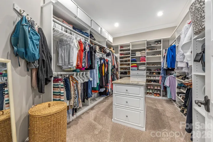 Primary closet includes ample storage with island for ease of packing and folding