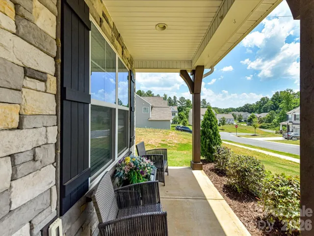 Inviting covered front entry with charming stone accents, decorative columns, and a cozy porch—perfect for welcoming guests or relaxing outdoors.