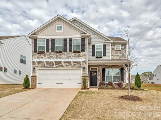 Beautiful two-story home featuring a charming stone façade, covered front porch, and spacious two-car garage, offering inviting curb appeal in a desirable community setting.