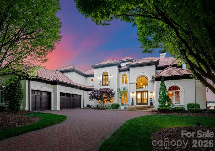 Elegant front elevation at twilight, featuring a paver driveway, grand entry, and timeless Mediterranean-inspired design