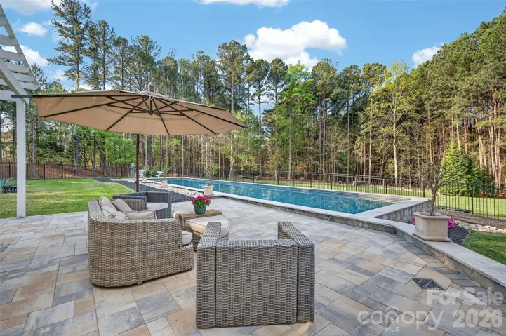 The heated saltwater pool is stunning - note the beautiful stonework framing the pool. Patio space, a pergola and a covered porch all combine for a versatile and expansive space to enjoy one of the most private and functional lots
