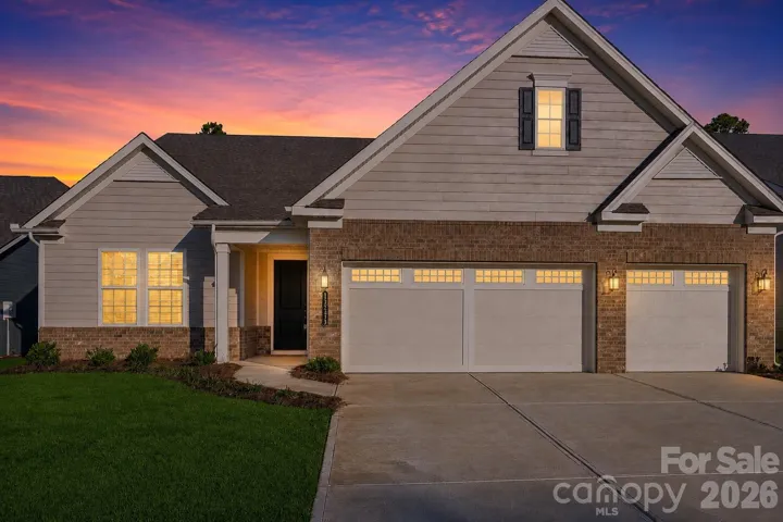 Twilight exterior showcasing the home's timeless curb appeal, inviting front porch, and spacious three-car garage.