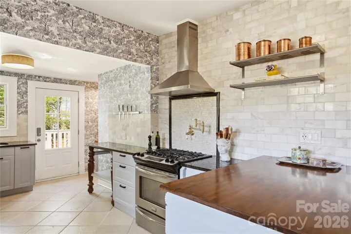 Open, spacious kitchen with granite countertops, gas range & matte gold pot filler