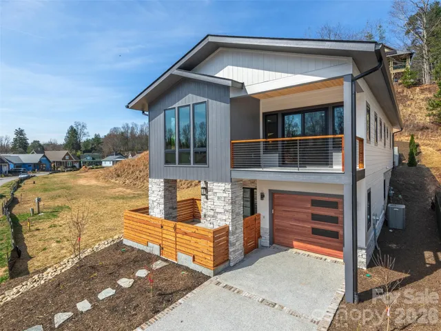 Front exterior of the completed Courtyard Villa showcasing modern mountain architecture, cultured stone accents, covered upper-level porch, private entry courtyard, and attached garage.