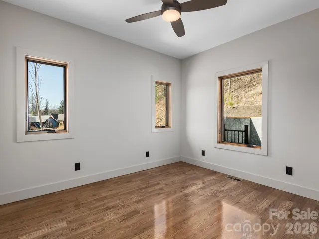 Representative photo from 50 Verde Drive showing the builder’s quality of construction and finish level, including a secondary bedroom with oak hardwood floors, ceiling fan, and abundant natural light.