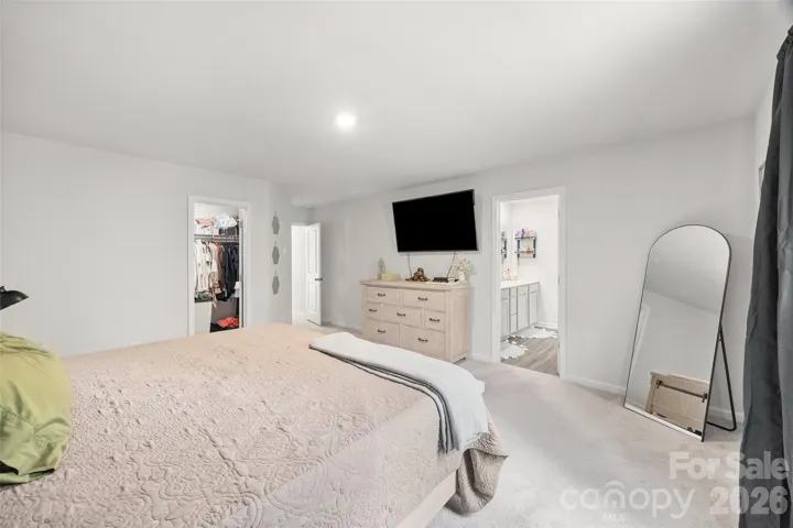 Upstairs primary bedroom featuring an ensuite bath and two large walk-in closets