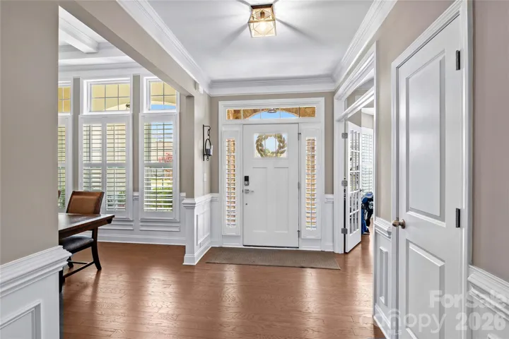 Impressive entry with crown molding, wainscotting and picture framing and upgraded lighting fixtures, sidelights with plantation shutters