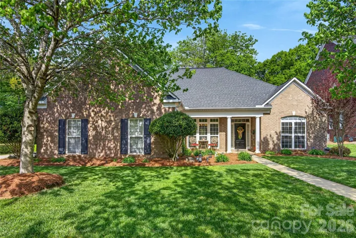 A beautifully maintained brick-front ranch framed by mature trees and well-maintained landscaping, with a level entry that creates an easy, inviting arrival.