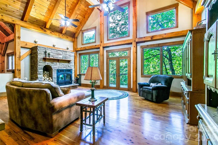Beautiful, light-filled open concept living area with year-round mountain view, vaulted ceiling, adjacent deck, large windows bringing the outdoors indoors, and wood-burning fireplace.