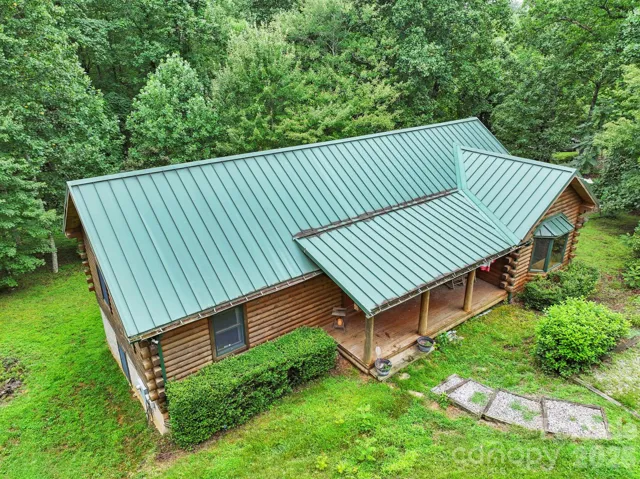 Aerial view showcasing the home’s metal roof, log exterior, and private wooded surroundings.