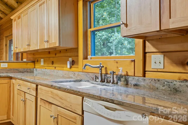 Close-up of granite countertops, stainless fixtures, and natural wood cabinetry highlighting quality craftsmanship.