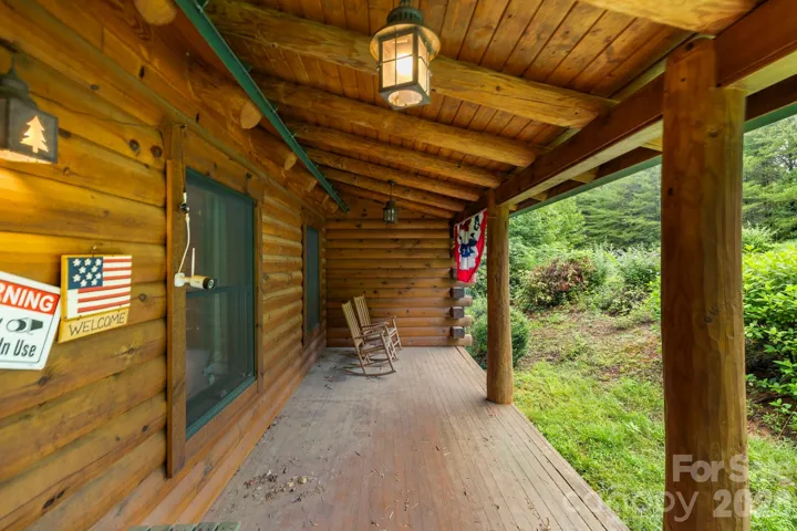 Covered front porch with rustic wood finishes and space for rocking chairs, perfect for enjoying quiet mornings or evening relaxation.