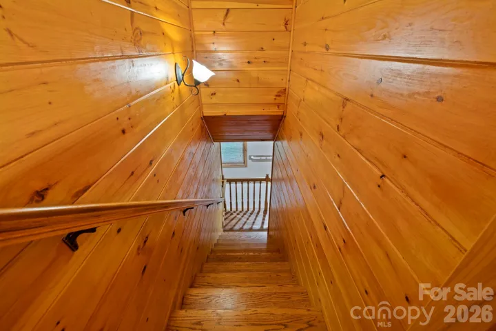 Stairway with rich wood detailing leading to the lower level, showcasing the home’s craftsmanship throughout.