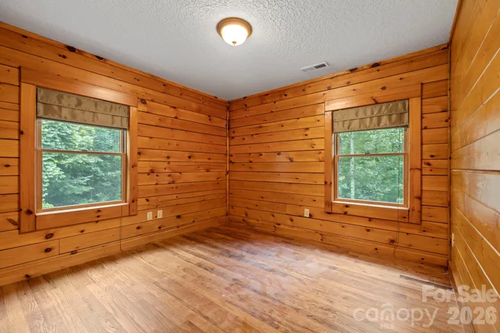 Bright corner bedroom with multiple windows, offering natural light and tranquil views.