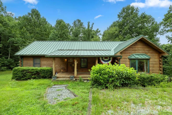 Classic log home with a durable metal roof, surrounded by lush greenery and offering a peaceful, private setting.