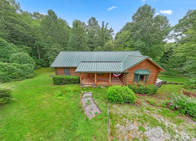 Charming front exterior with covered porch, nestled in a lush, serene landscape.