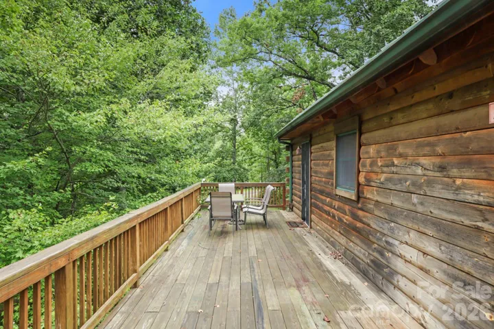 Private back deck surrounded by mature trees, ideal for relaxing or enjoying the peaceful natural setting.