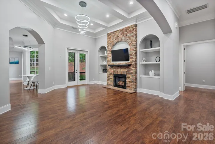 Formal living room includes stacked stone fireplace, built ins and tray ceiling