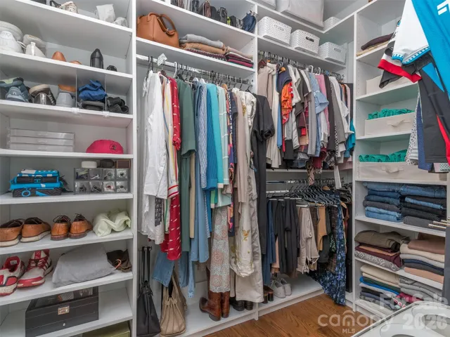 Walk In Primary Closet with Custom Shelving & Hardwood Floors