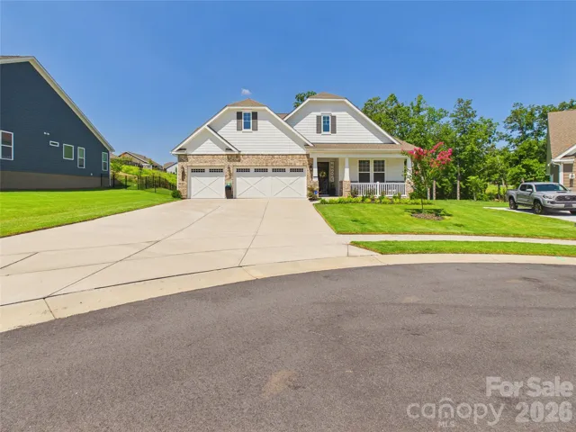 Beautiful home with inviting curb appeal, featuring a blend of brick and siding, a welcoming covered front porch, and a spacious three-car garage. Professionally landscaped with a lush lawn and manicured shrubs, the home is enhanced by warm exterior lighting and charming architectural details.
