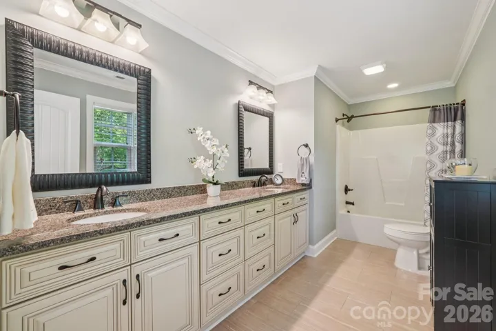 Primary bath has dual basin vanity with granite countertop and tile floor.