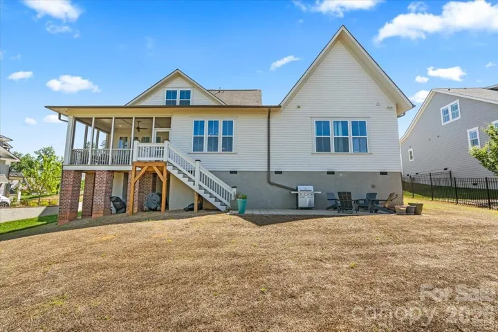 The screen porch overlooks an open, flat back yard backed by a beautiful treescape.