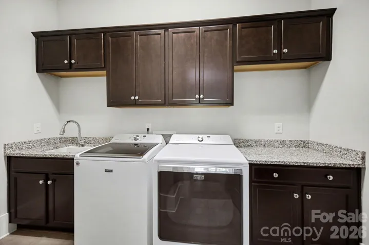 Laundry room with sink, granite countertops, cabinetry and folding area