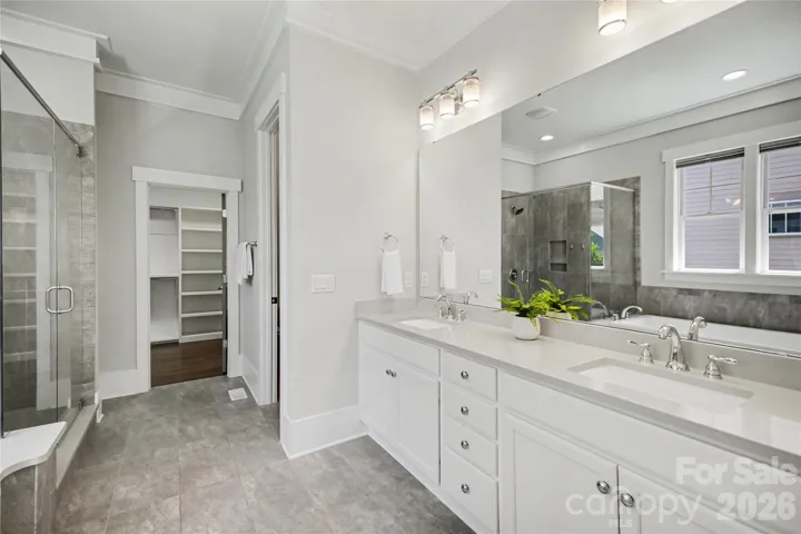 Spa-like bath with quartz countertops and direct access to walk-in closet.